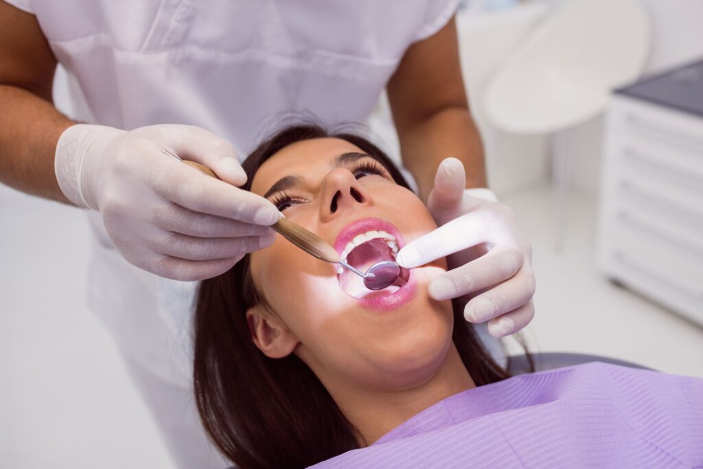 dentist examining patient teeth with mouth mirror min dentist examining patient teeth with mouth mirror min