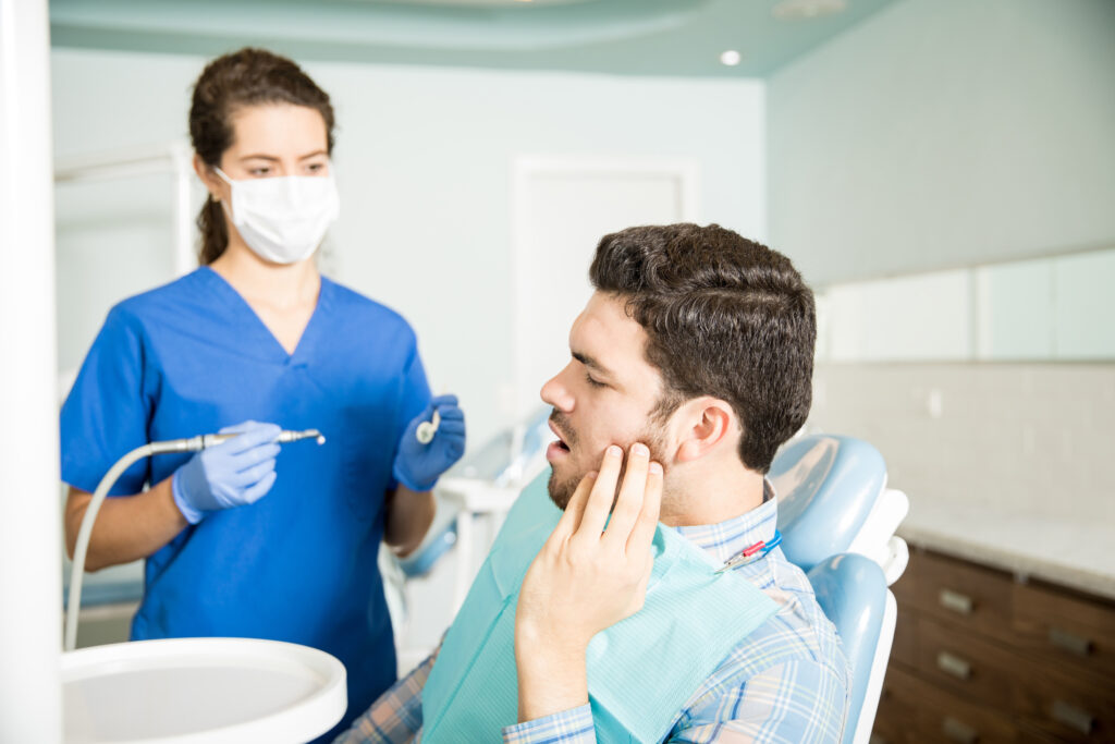 mid adult man suffering from toothache while looking dentist with tools clinic mid adult man suffering from toothache while looking dentist with tools clinic